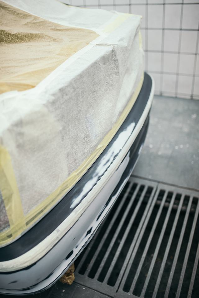 Een wagen in de werkplaats, de achterkant met papier en tape afgeplakt voor het spuiten